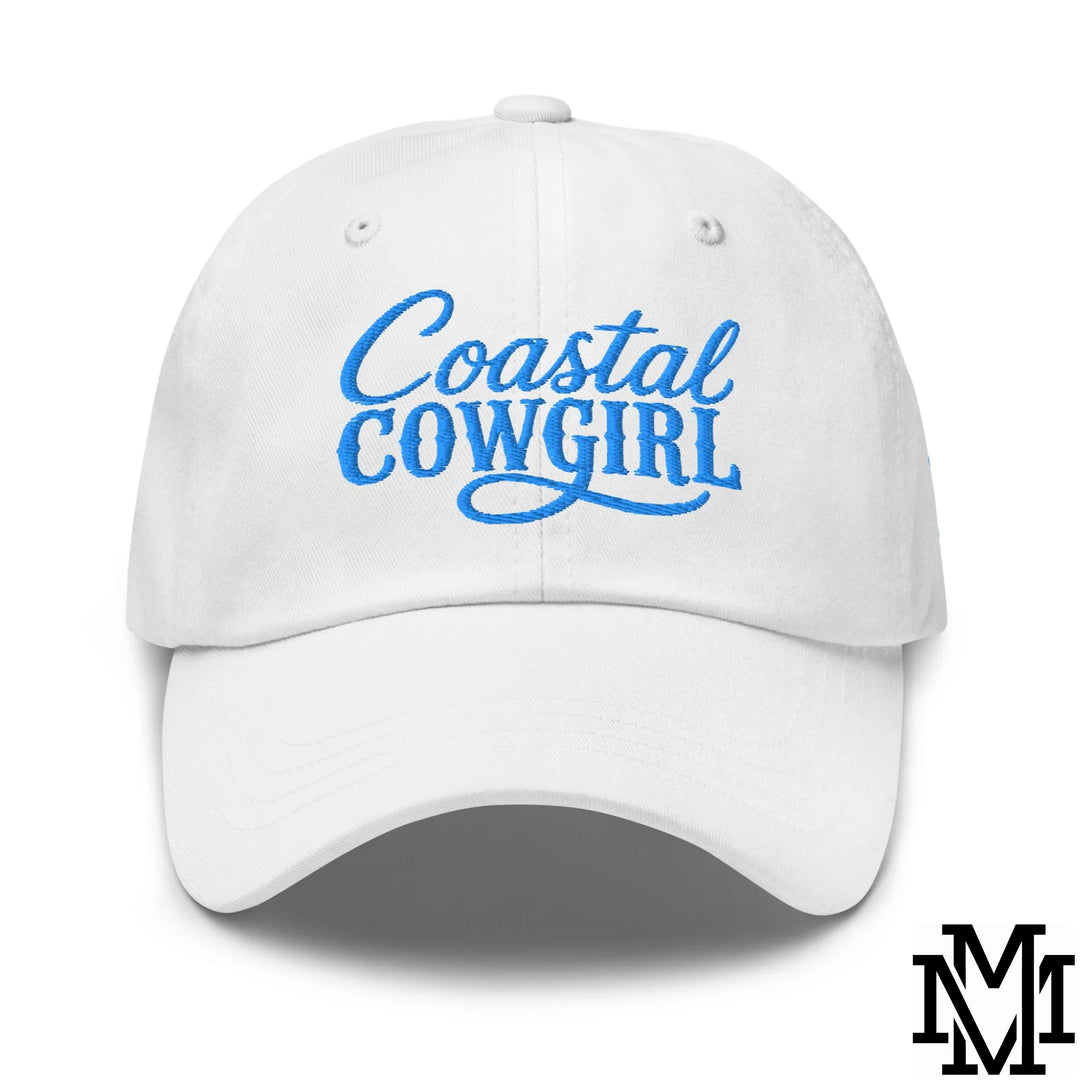 White cotton baseball cap with blue embroidered coastal cowgirl cursive text featured in dad hat article.