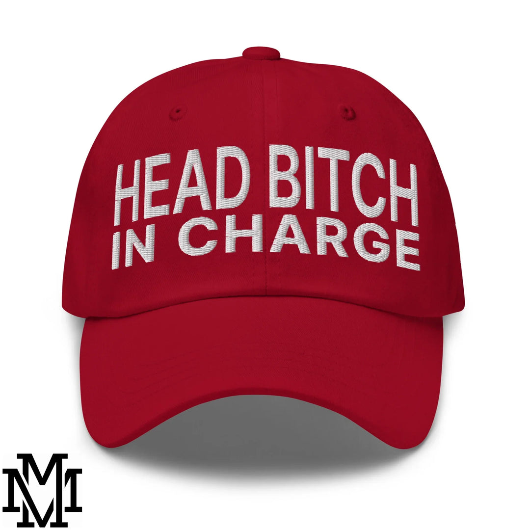 A vibrant red cotton dad hat with bold white embroidered text head bitch in charge as a power accessory