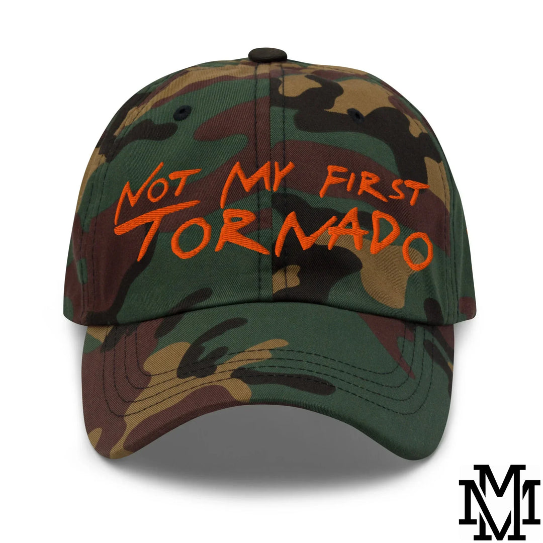 A camouflage baseball cap with orange embroidered text not my first tornado featured in storm-proven style dad hats