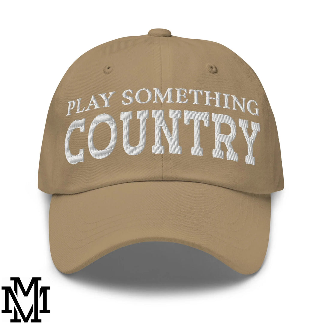 Tan baseball cap with white embroidered play something country text in bold font featured in a dad hat article