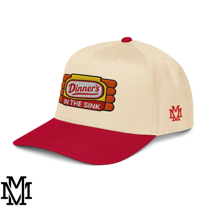 Cream-colored baseball snapback hat with red brim and embroidered dinner’s in the sink logo on the front