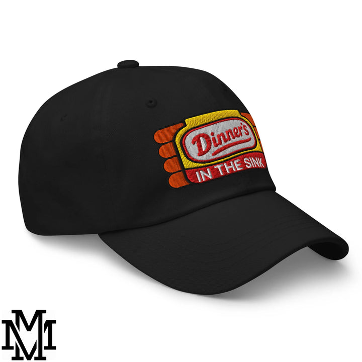 Black unstructured dad hat featuring an embroidered dinner’s in the sink patch in red on yellow and orange background