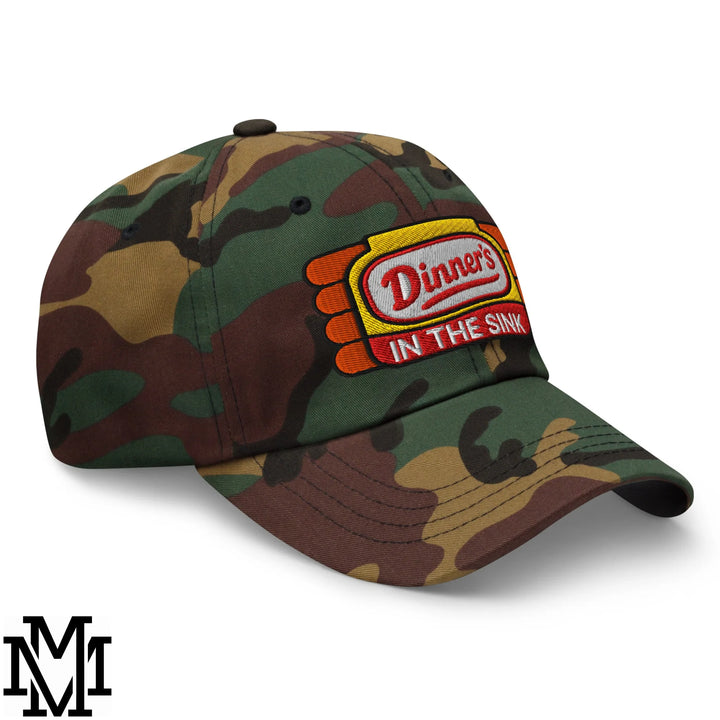 Camouflage dad hat with colorful embroidered patch reading dinners in the sink on front panel