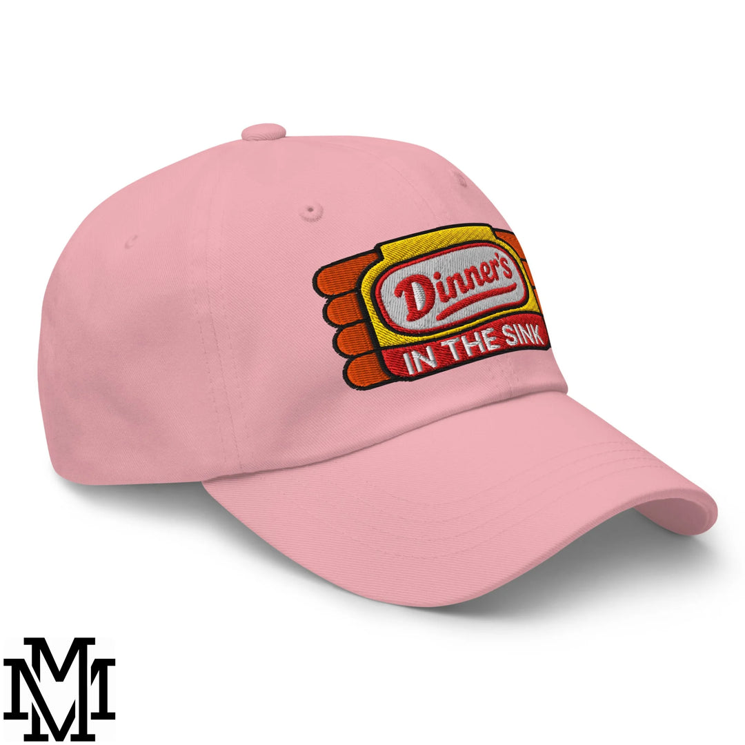 Pink unstructured dad hat featuring an embroidered dinner’s in the sink logo in yellow and red design