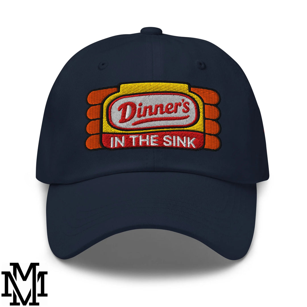 Navy blue unstructured dad hat with embroidered dinner’s in the sink logo in red and white on yellow orange background