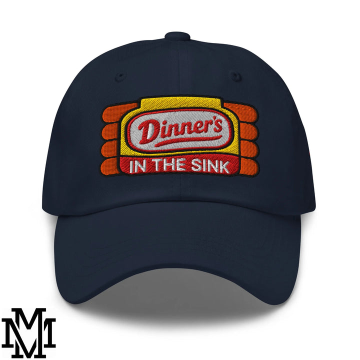 Navy blue unstructured dad hat with embroidered dinner’s in the sink logo in red and white on yellow orange background