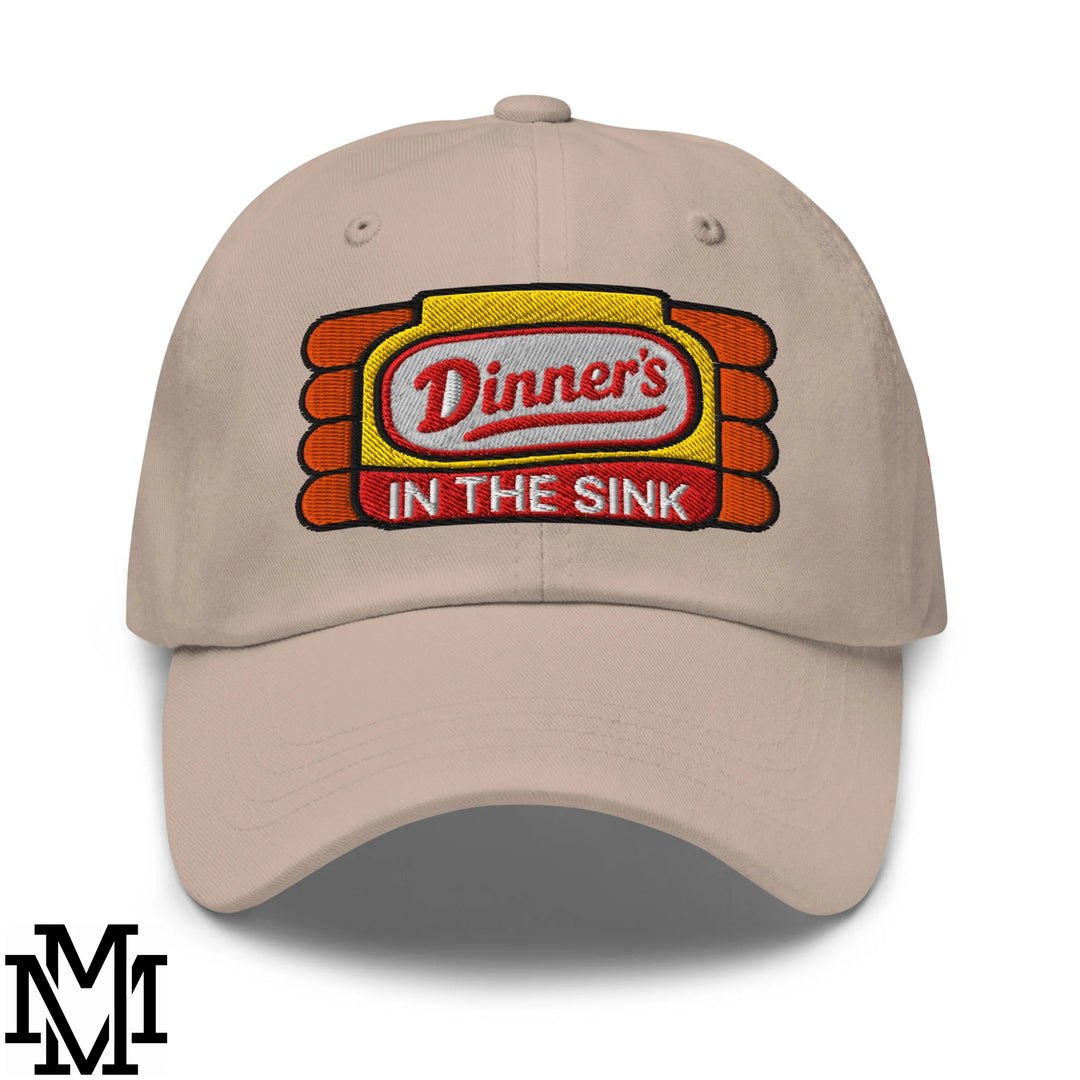 Beige unstructured dad hat with embroidered dinner’s in the sink logo in red on yellow and orange background