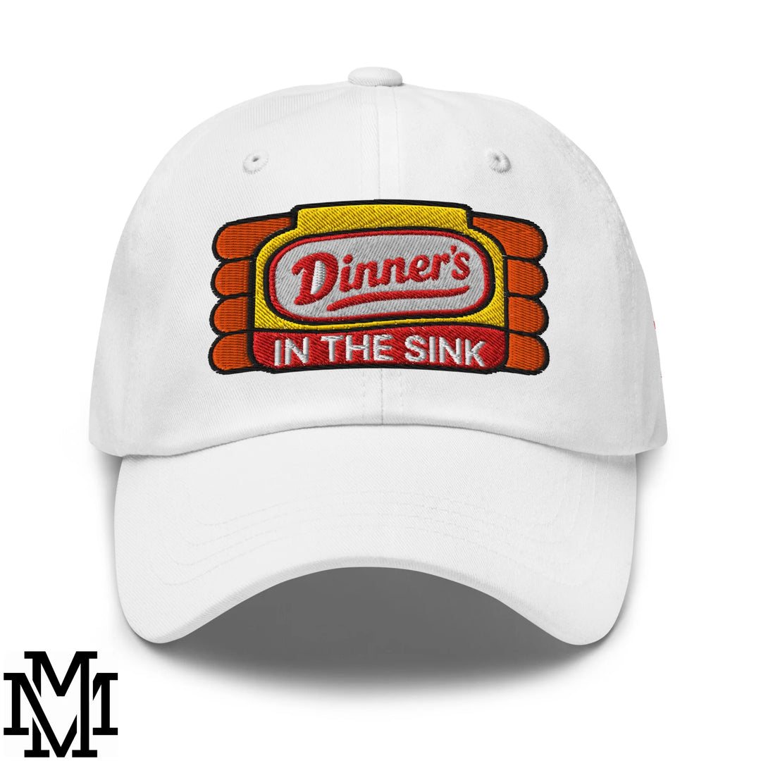 White unstructured dad hat featuring an embroidered dinner’s in the sink patch in red black and yellow with orange stripes