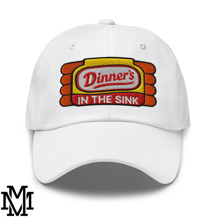 White unstructured dad hat featuring an embroidered dinner’s in the sink patch in red black and yellow with orange stripes