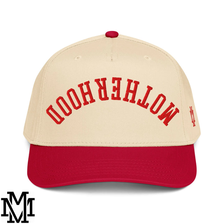 Cream-colored baseball cap with red embroidered motherhood arch and matching red brim in upside down motherhood snapback hat